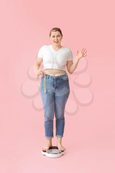 Overweight woman standing on scales against color background. Weight loss concept�
