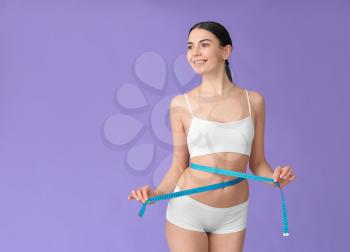 Young woman with measuring tape on color background. Weight loss concept�