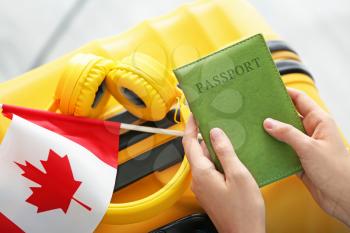 Woman with passport, Canadian flag and luggage, closeup. Travel and immigration concept�