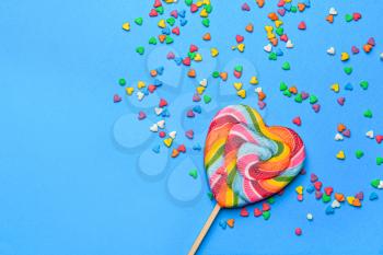 Tasty lollipop with sprinkles on color background�
