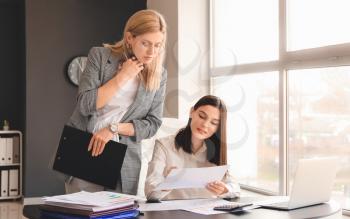 Young female accountant with colleague working in office�
