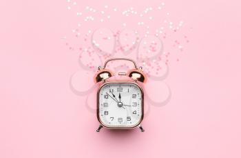 Alarm clock with confetti on color background�