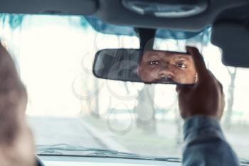 Driver adjusting rear view mirror in car�