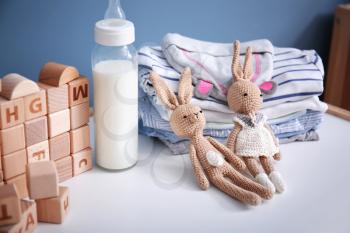 Toys with baby bottle of milk and clothes on table at home�