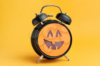 Alarm clock with scary face on color background. Halloween celebration�