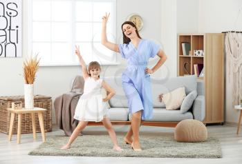Happy mother and her little daughter dancing at home�