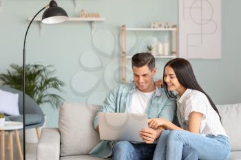 Happy young couple with laptop at home�