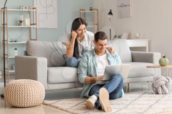 Happy young couple with laptop at home�