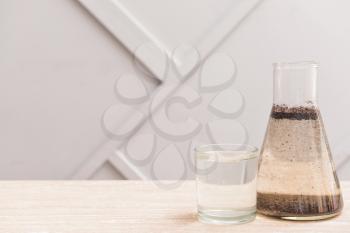Glass and flask with clean and dirty water on table�