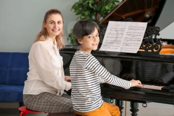 Private music teacher giving piano lessons to little boy�