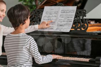 Private music teacher giving piano lessons to little boy�