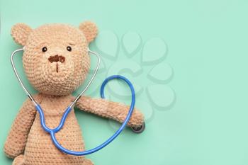 Stethoscope and baby toy on color background�