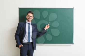 Male teacher near blackboard in classroom�