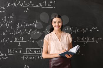 Female teacher near blackboard in classroom�