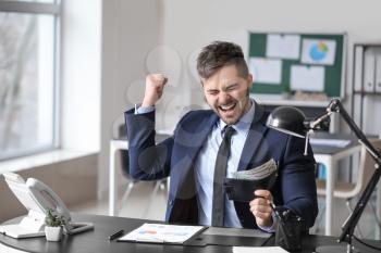 Happy businessman with purse in office�