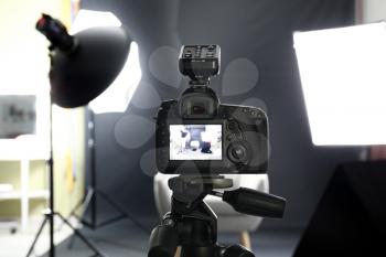 Professional camera on tripod in modern photo studio�