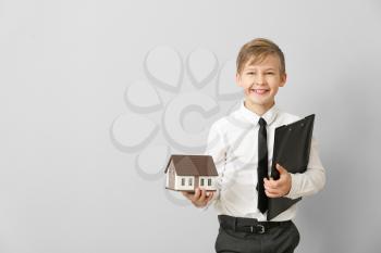 Portrait of little real estate agent with model of house on light background�