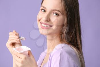 Young woman with tasty yogurt on color background�