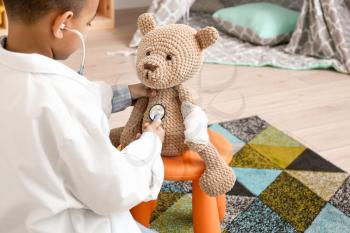 Cute little African-American boy playing doctor at home�
