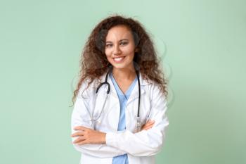 Young African-American doctor on color background�