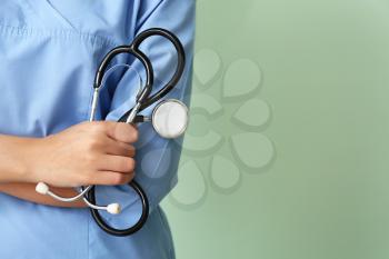 Young African-American nurse with stethoscope on color background, closeup�