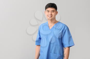 Male Asian doctor on light background�