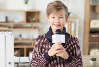 Little journalist with microphone having an interview in office�