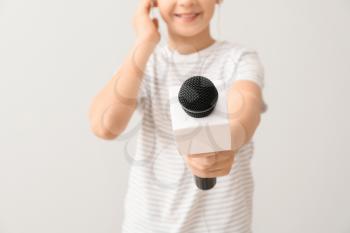Little journalist with microphone on white background�