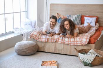 Happy young couple playing video games in bedroom�