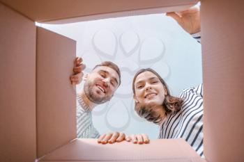 Young couple looking inside cardboard box, bottom view�
