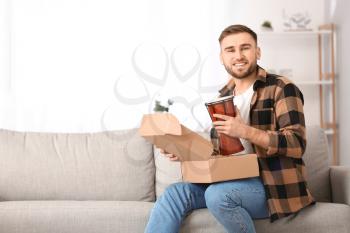 Young man unpacking parcel at home�