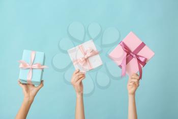 Female hands with beautiful gift boxes on color background�