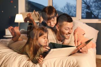 Father and his little children reading bedtime story at home�