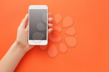 Female hand with mobile phone on color background�