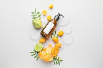 Cosmetic product in bottle and citrus fruits on white background�