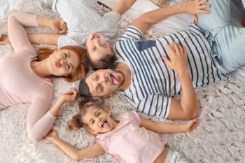 Happy family having fun on bed at home�