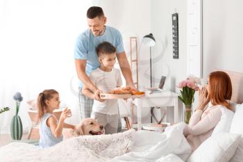 Happy husband with children bringing his wife breakfast in bed�