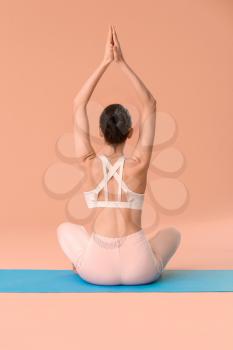 Young woman practicing yoga on color background�