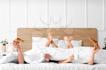 Young couple having breakfast in bed at home�