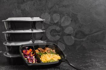 Containers with healthy food on dark background�