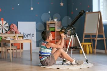 Little African-American boy with telescope looking at stars in evening�