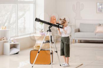 Cute little traveler with telescope at home�