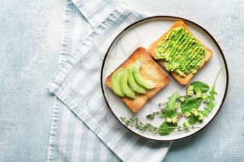 Plate with tasty avocado sandwiches on color background�
