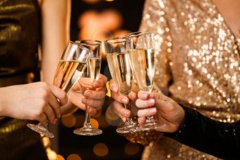 Women clinking glasses of tasty champagne at party�