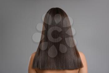 Young woman with beautiful straight hair on grey background�