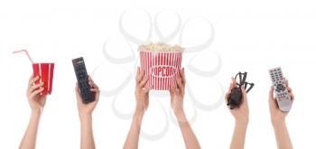 Many hands with popcorn, drink, remote controls and eyeglasses on white background�