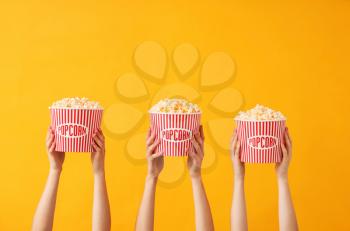 Many hands with popcorn in buckets on color background�