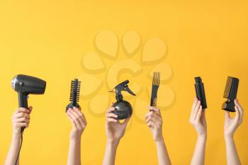 Many hands with hairdresser's supplies on color background�