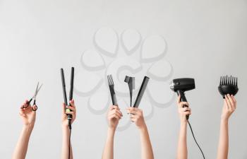 Many hands with hairdresser's supplies on grey background�