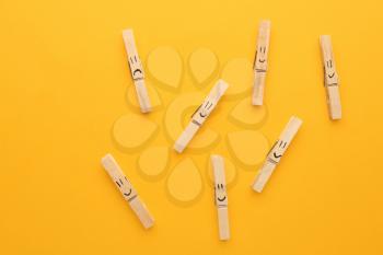 One clothes peg with drawn sad face among happy ones on color background. Concept of depression�